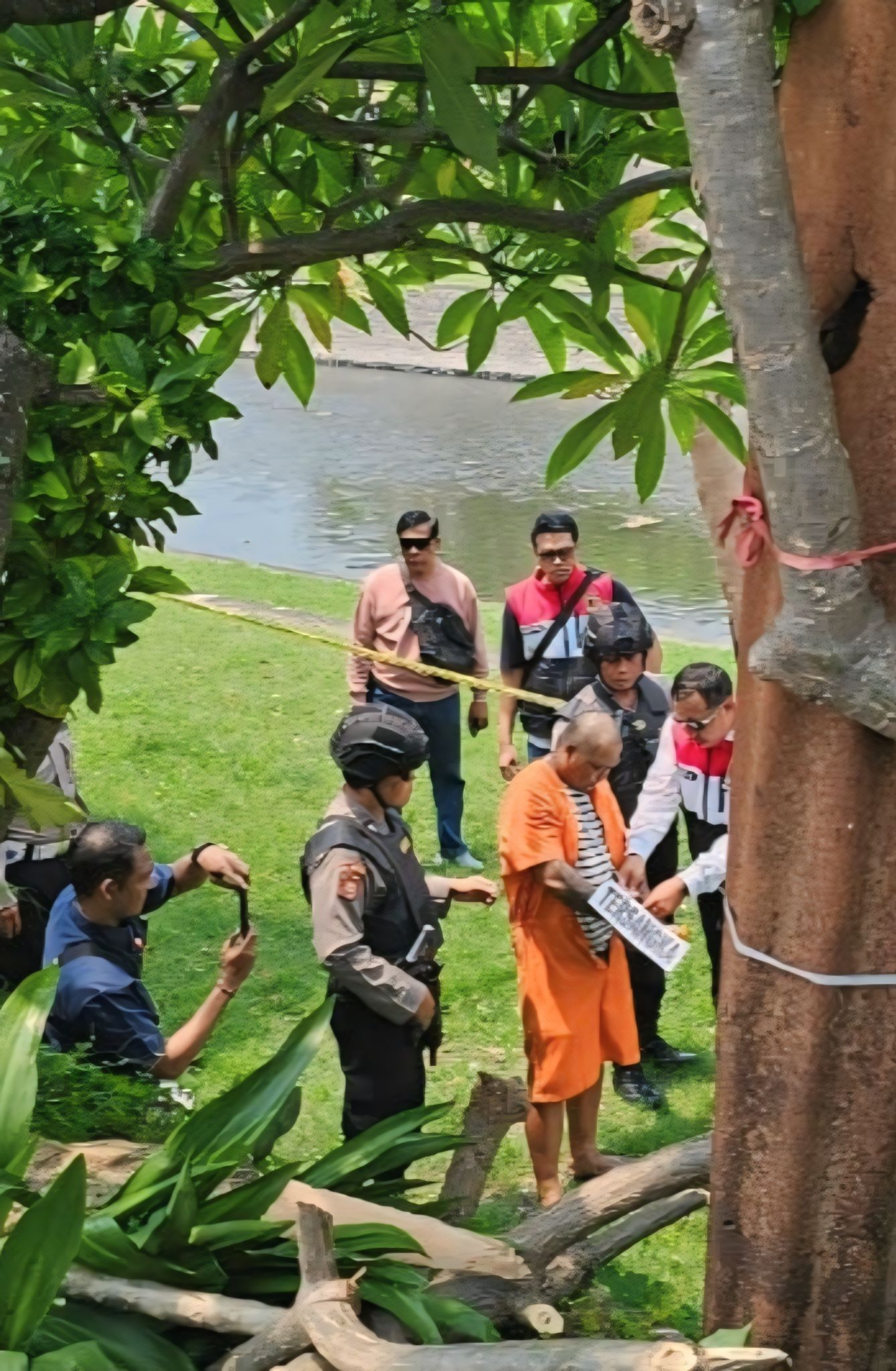 Agus Sugianto saat memperagakan reka ulang adegan pembunuhan jukir Komang Asmara di bantaran sungai Taman Pancing. (Bali Express/Istimewa)