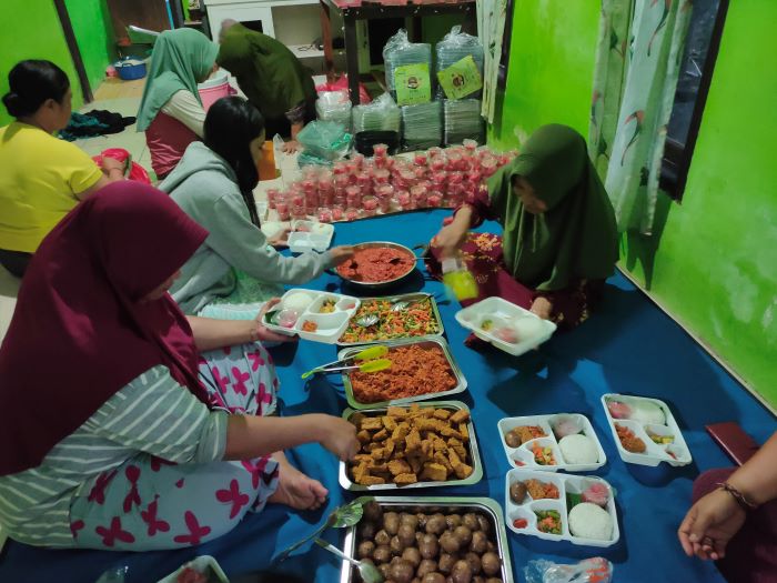 Ibu PKK Desa Sumberklampok menyiapkan paket uji coba program makan bergizi gratis untuk ratusan siswa.