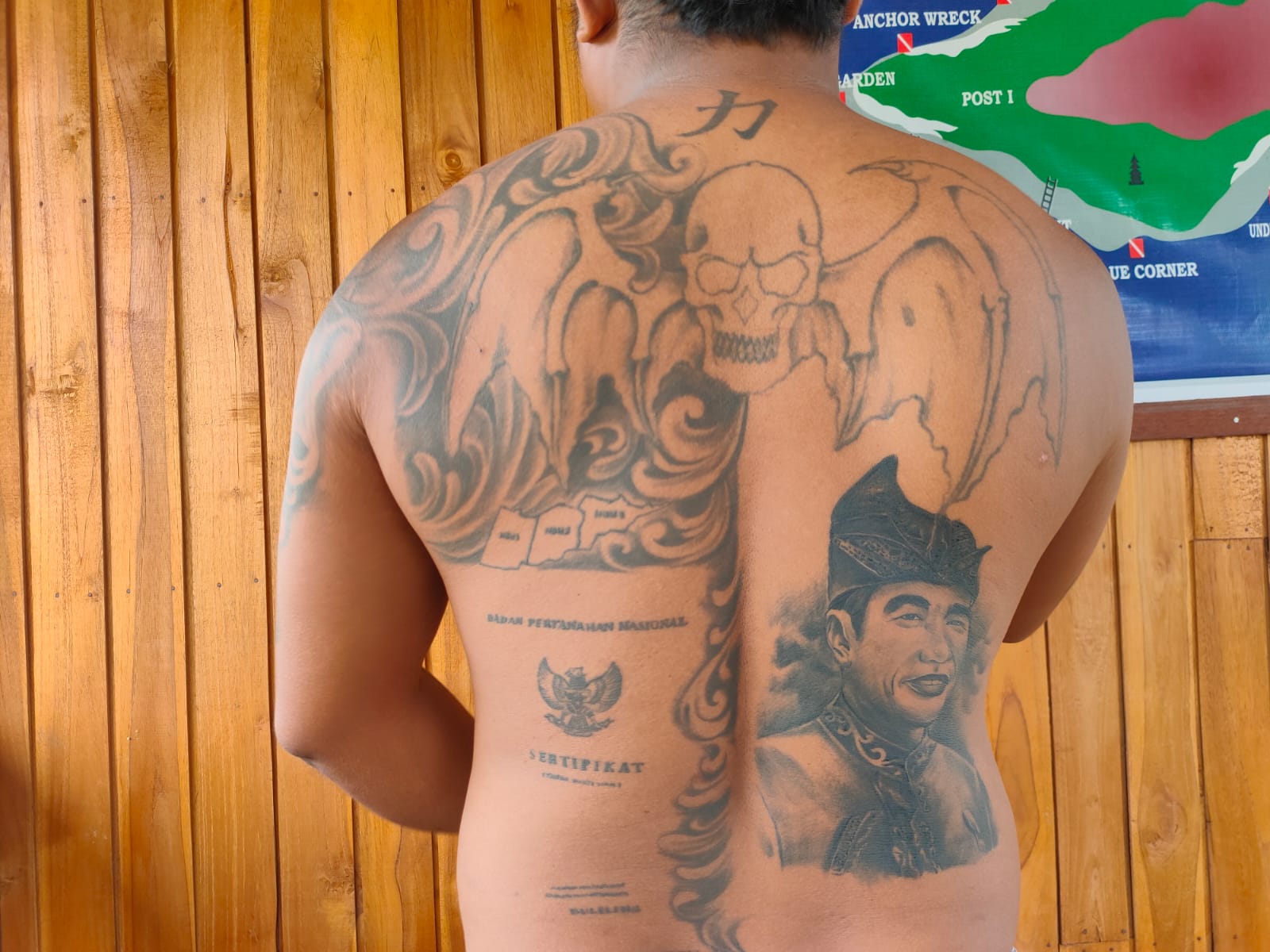 Punggung Kadek Agus Wijaya yang penuh tato perjuangan tanah di Desa Sumberklampok, Kecamatan Gerokgak. Ada tato wajah Jokowi juga yang membuat sertifikat itu sampai ke tangannya.