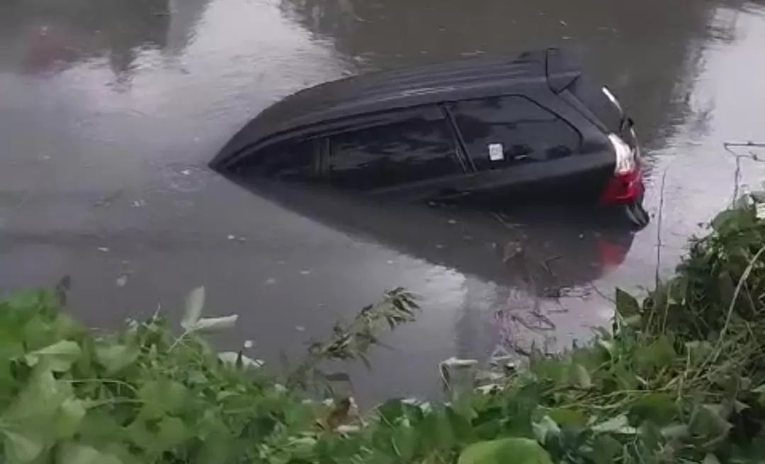 Mobil tercebur akibat terseret pohon tumbang di Jalan Dharmahusada Indah, Surabaya. (IST)