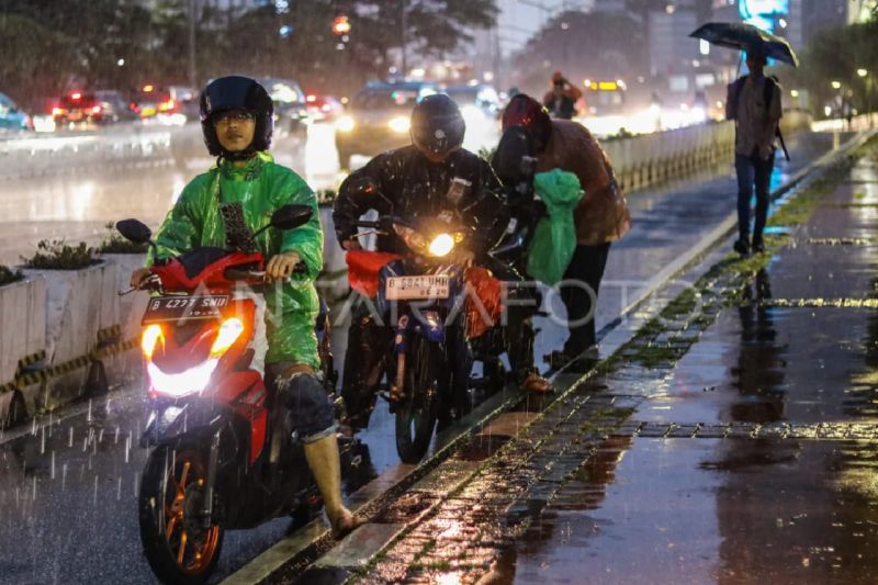 Ilustrasi - Sejumlah pengendara motor berhenti untuk memakai jas hujan.