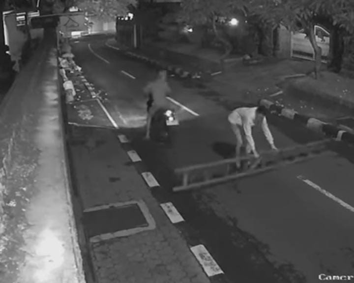 Dua orang pemuda di Denpasar meletakkan tangga kayu di tengah jalan hingga bahayakan pengguna jalan