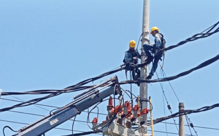Petugas PLN sedang bertugas memperbaiki kabel pada gardu milik PLN.