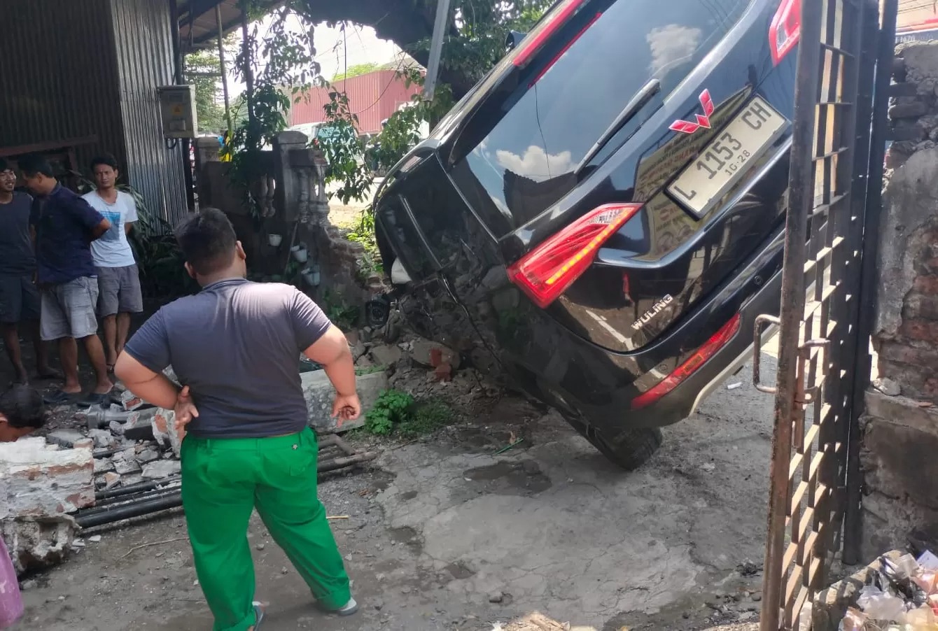 TERGULING: Gara-gara menghindari pemotor melintas mendadak, mobil Wuling tabrak pagar dan pohon di Jalan Raya Taman, Sidoarjo, Kamis (9/1) siang.