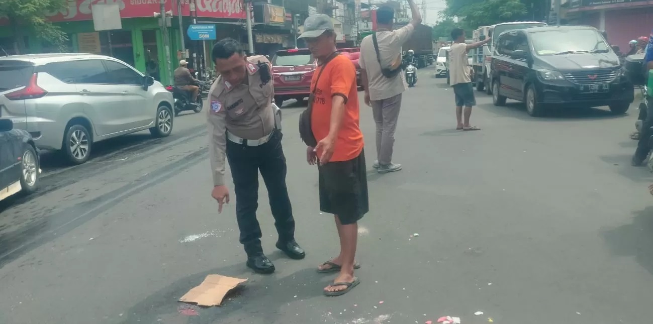 MENINGGAL : petugas menunjukkan lokasi kecelakaan antara sepeda motor dengan truk tangki di Simpang Lima Krian, Sidoarjo, Senin (20/1). (IST/RADAR SIDOARJO)