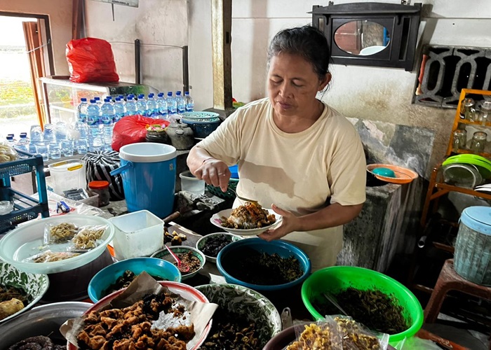 Menantu Mek Losi menyajikan seporsi nasi campur babi untuk pembeli.