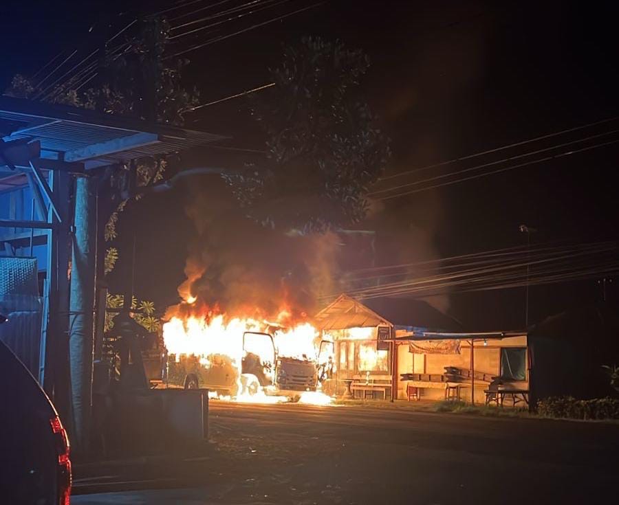 TERBAKAR : Mobil Travel yang terbakar dan api merembet ke tempat usaha potong rambut di Desa Banyubiru, Kecamatan Negara, Jembrana, Minggu (26/1/2025) (Istimewa).