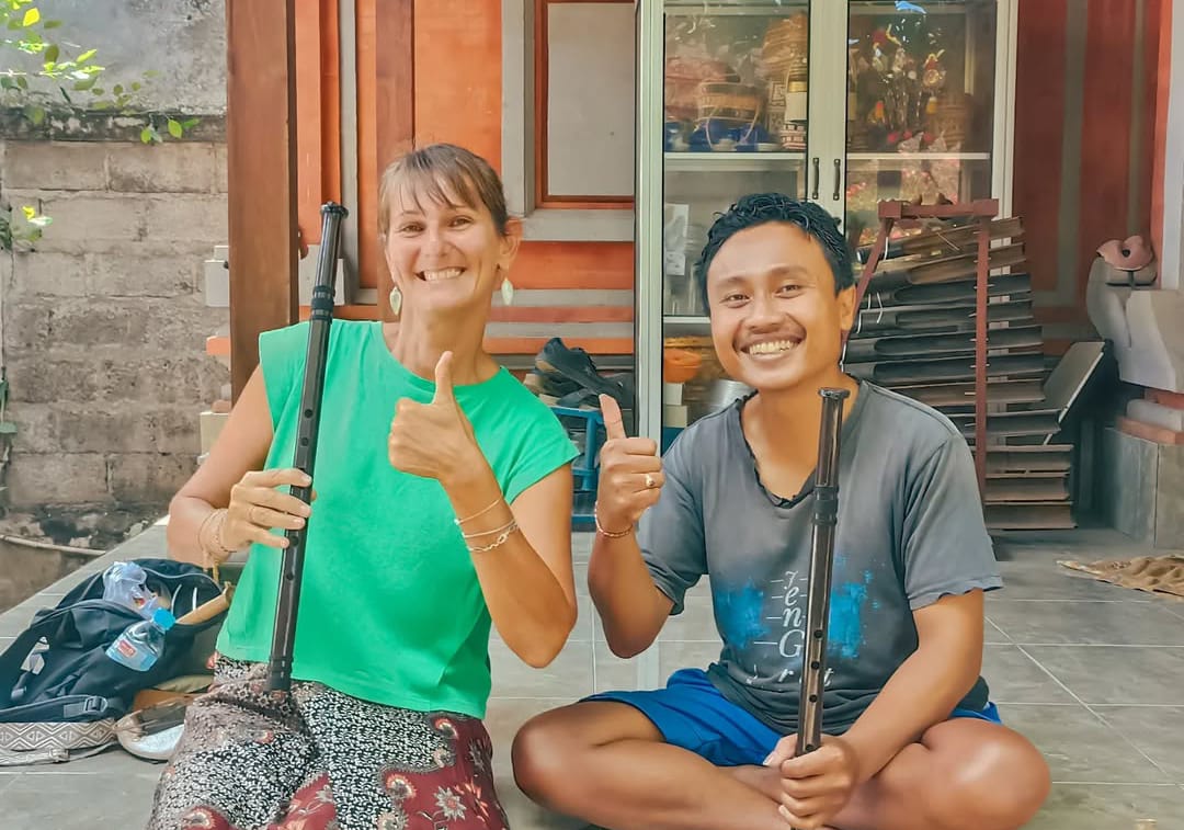 KREATIVITAS: Dek Adi ketika bersama pembeli suling buatannya di Banjar Pasdalem Kelod, Kelurahan Gianyar