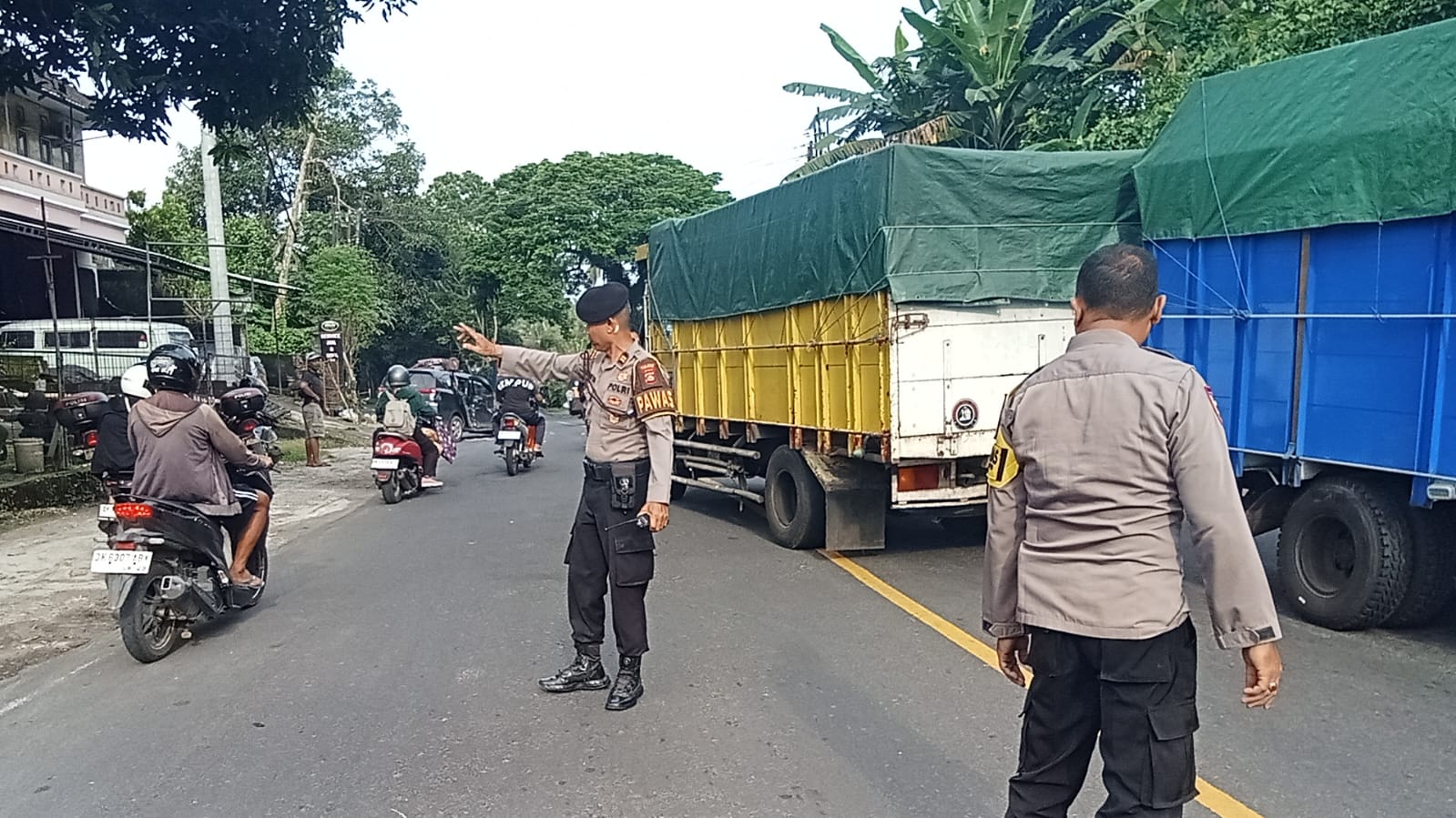 Personel dari Polsek Selemadeg Timur melakukan pengaturan Lalu lintas selama proses evakuasi daihatsu Sigra yang mengalami kecelakaan di jalur tengkorak Tabanan.