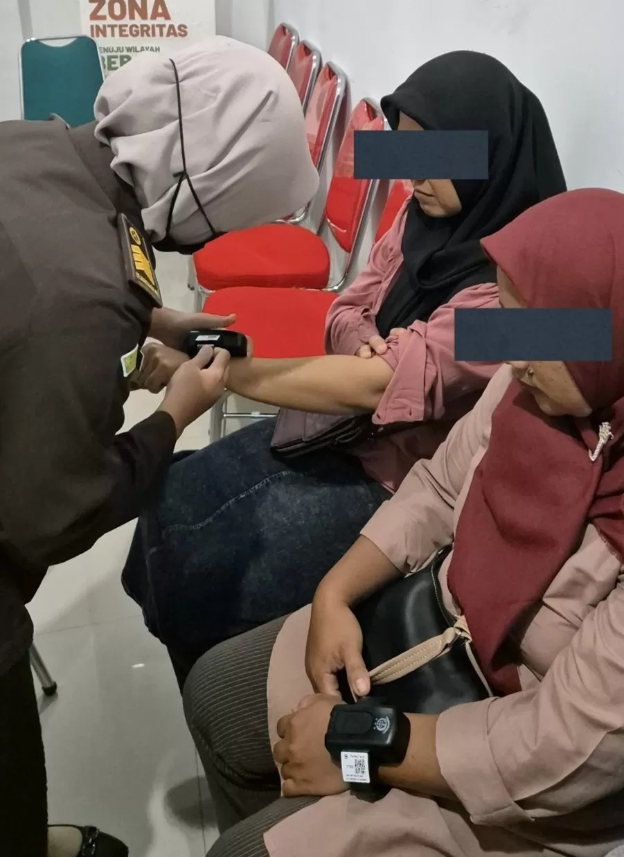EMAK-EMAK: Petugas Kejari Boyolali memasang alat detection kit di pergelangan tangan emak-emak tersangka penganiayaan anak bawah umur.