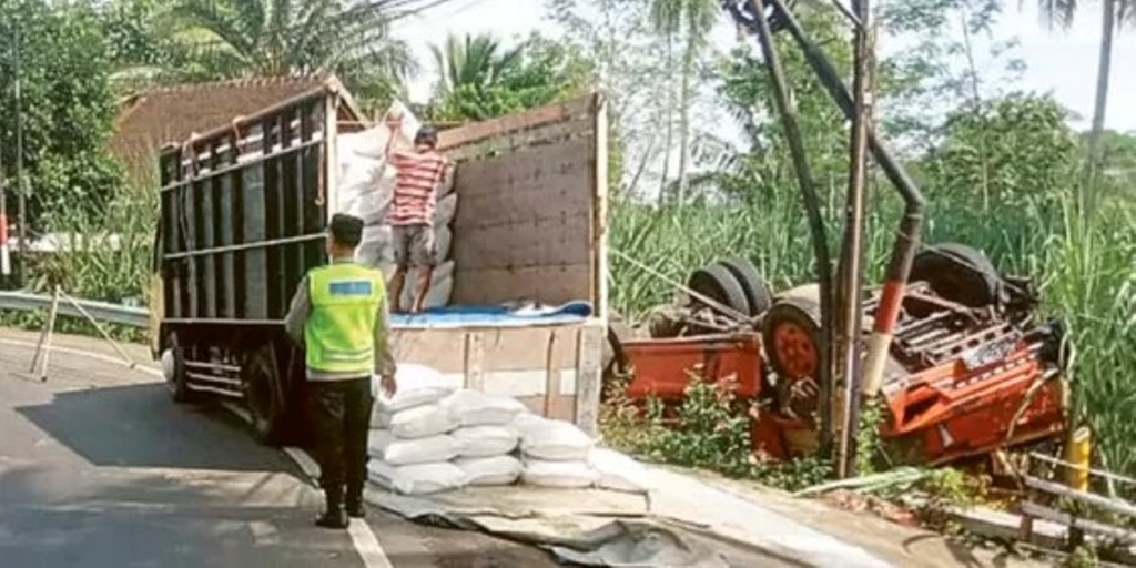 EVAKUASI: Truk pengangkut beras terbalik di tikungan Jalan Raya Sukorame, Desa Bumirejo, Kecamatan Dampit kemarin (18/2). Beras yang berserakan terpaksa dipindah ke truk lain.