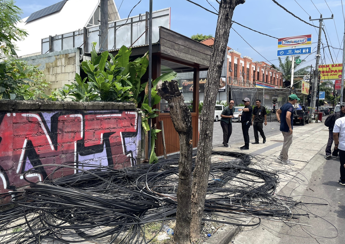 PEMBERSIHAN: Tim PJUT Pemkab Badung saat melakukan pembersihan kabel provider di Jalan Dewi Sri, Kecamatan Kuta, Rabu (19/2).