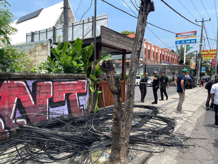 PEMBERSIHAN: Tim PJUT Pemkab Badung saat melakukan pembersihan kabel provider di Jalan Dewi Sri, Kecamatan Kuta, Rabu (19/2).
