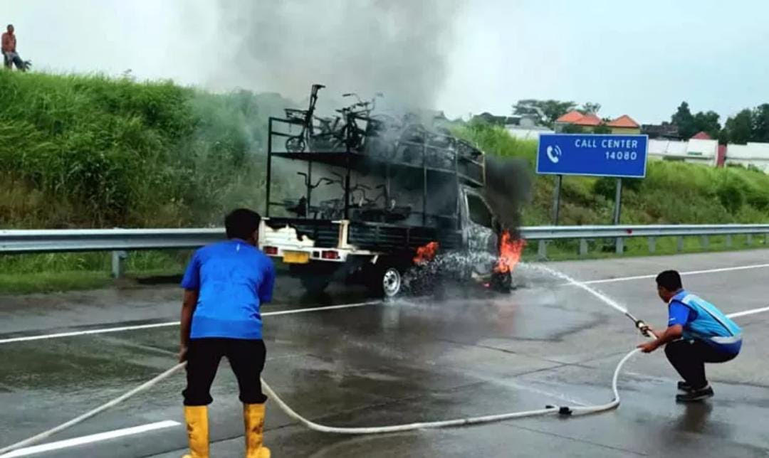 Petugas saat berupaya memadamkan api yang melalap pikap muat motor listrik di Tol Gempol-Pasuruan.