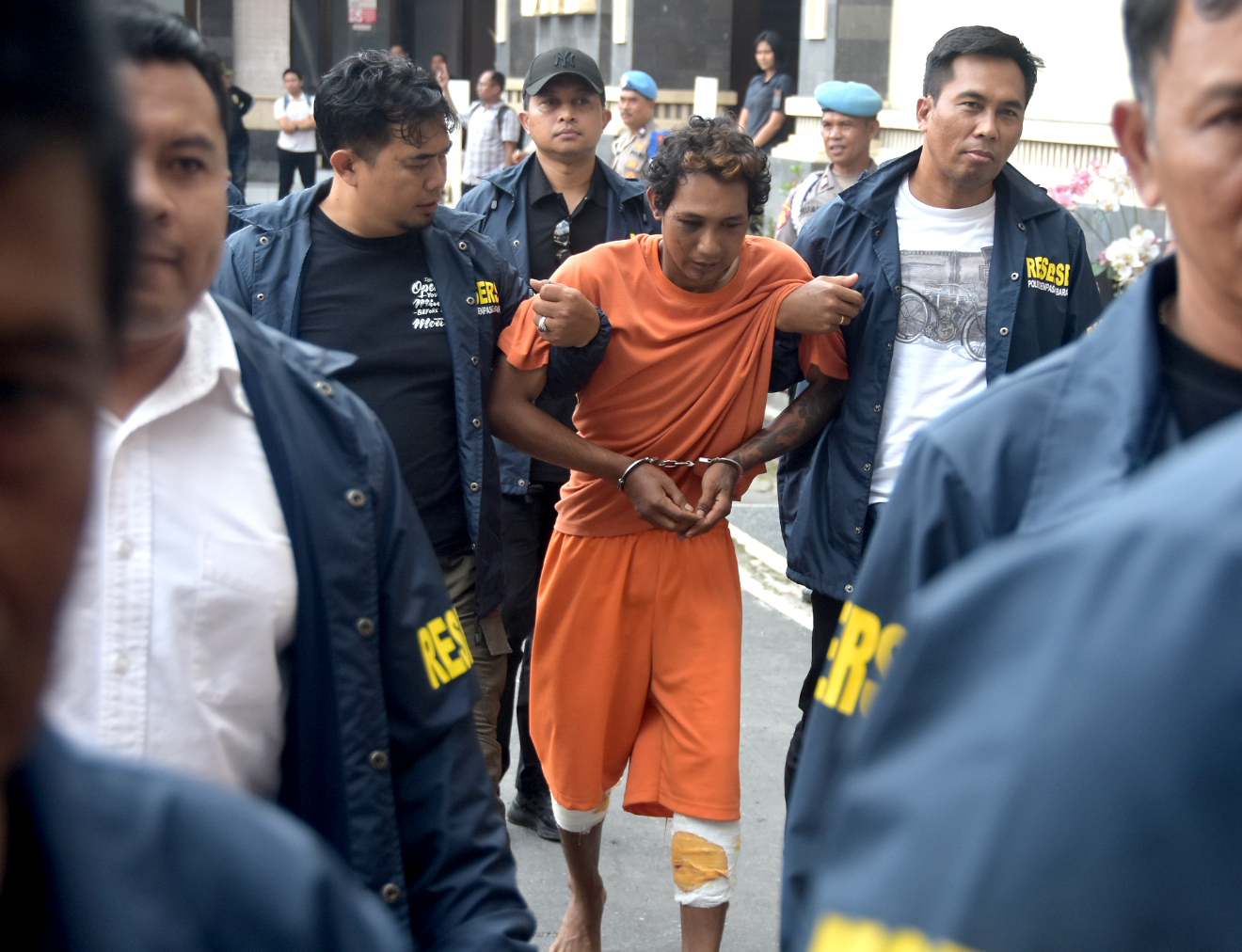 DIGIRING: Tersangka Ahmad Santoso digiring di Mapolresta Denpasar dengan kedua kaki diperban.