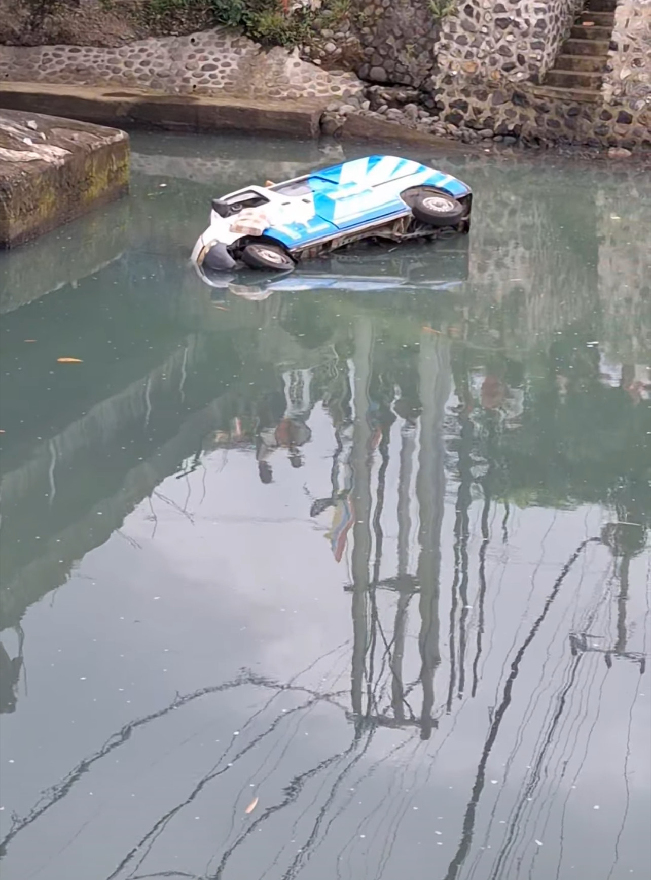 TERENDAM: Mobil ambulan berisi jenasah terjun ke sungai di Desa Yehembang, Kecamatan Mendoyo, Senin (24/3/2025).