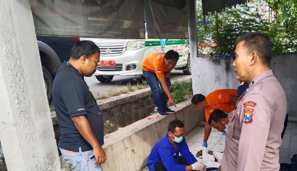 TKP: Petugas di lokasi penemuan pegawai Dinas Perhubungan Jombang, Raden Roby Hary Yanto, 45, meninggal di emperan rumah kosong Desa Palrejo, Sumobito, Jumat (18/4) pagi. (Achmad RW/Radar Jombang)