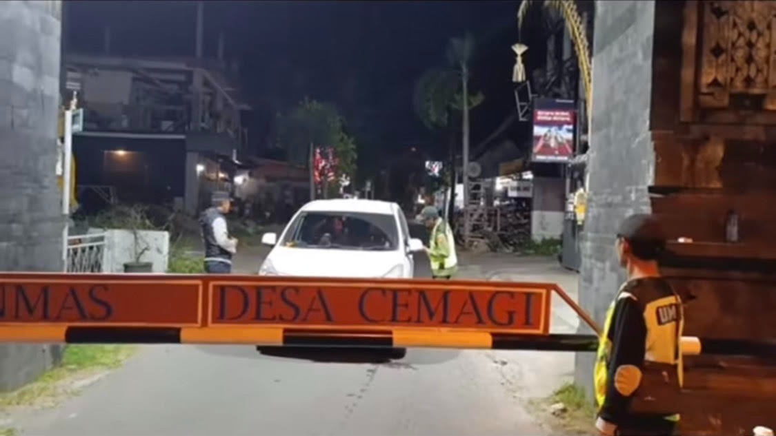 PENJAGAAN: Petugas Linmas Desa Cemagi melakukan pemeriksaan terhadap masyarakat atau wisatawan yang ingin memasuki desa tersebut.