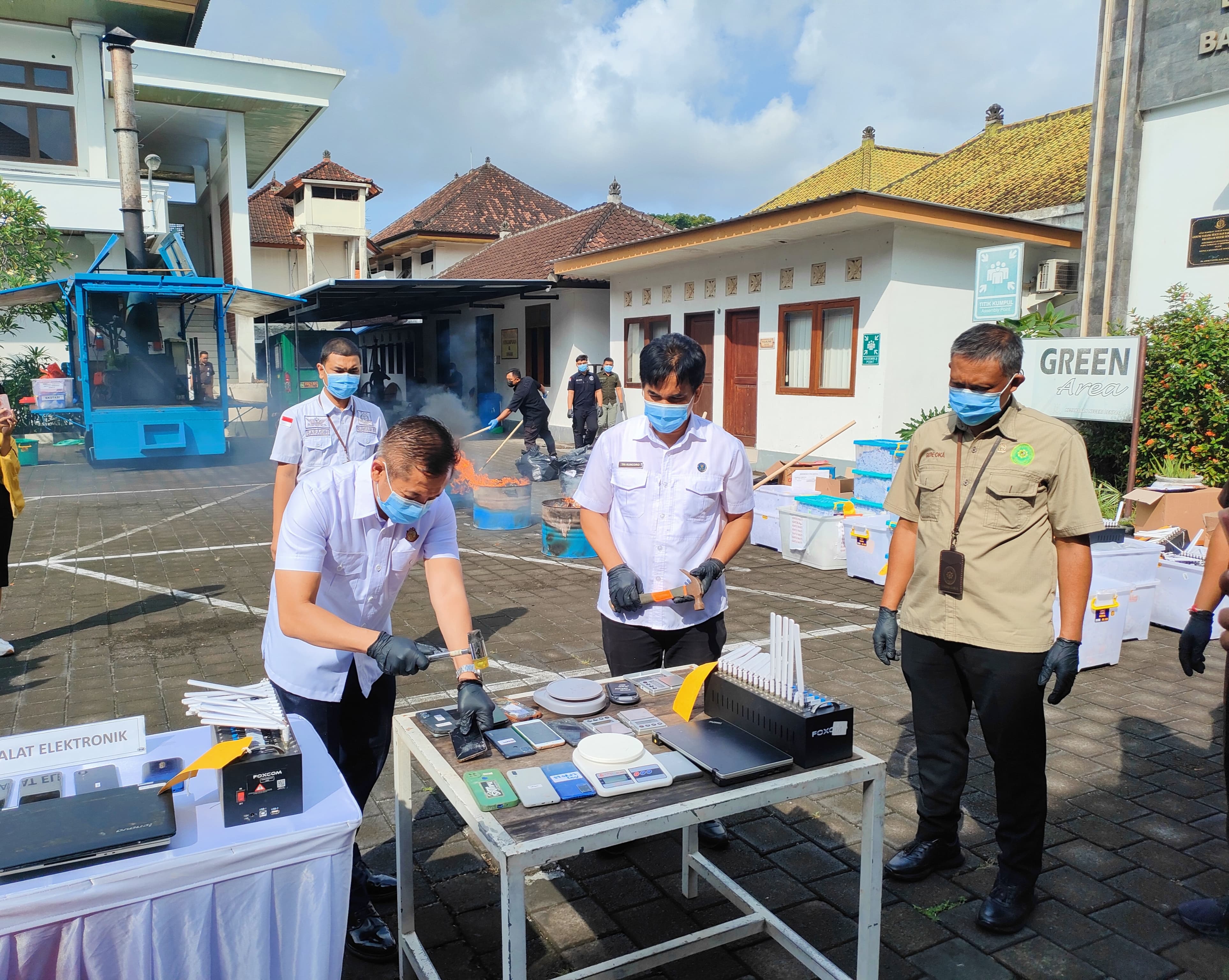 Kepala Kejari Denpasar Agus Setiadi (kiri) menghancurkan barang bukti handphone menggunakan palu. (Bali Express/I Gede Paramasutha)