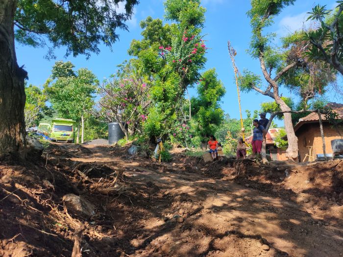 Warga di perbatasan desa Depaha-Desa Bukti sedang melihat truk yang membawa material untuk perbaikan jalan dalam program TMMD ke-124.