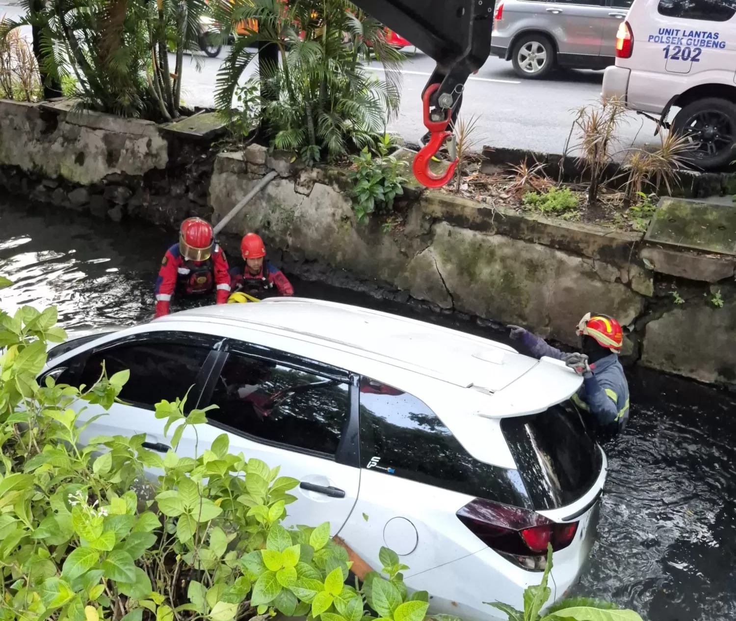 MASUK SUNGAI: Mobil Mobilio yang tercebur di sungai Jalan Nginden Kota, Surabaya, Minggu (1/6) pagi.