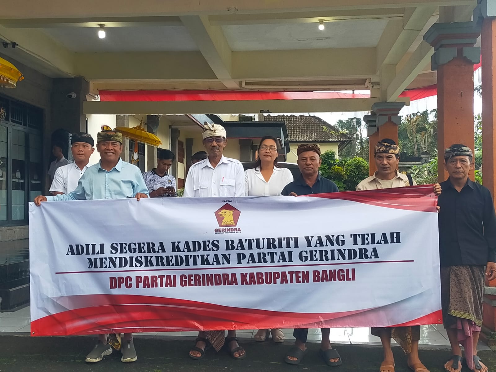 Pengurus DPC Gerindra membawa spanduk saat melaporkan Perbekel Baturiti I Made Suryana ke Polres Bangli, Jumat (13/6/2025).