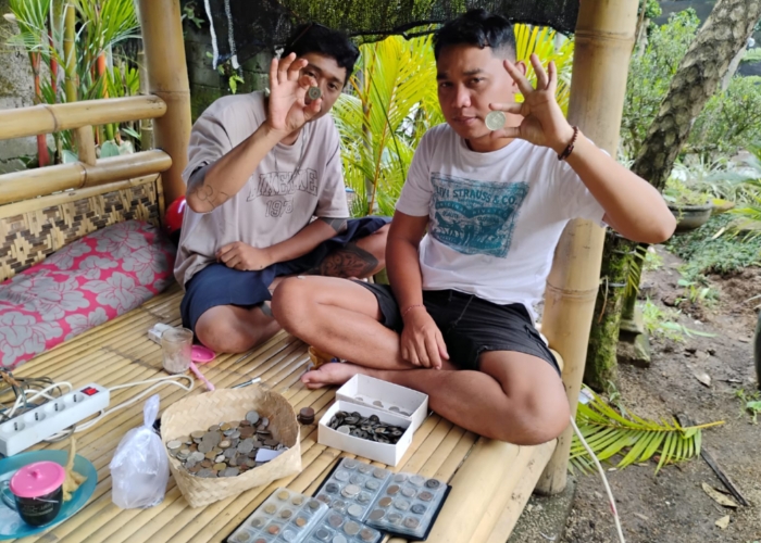 KOLEKSI : Kadek Oka menunjukkan koleksi koin kuno miliknya.