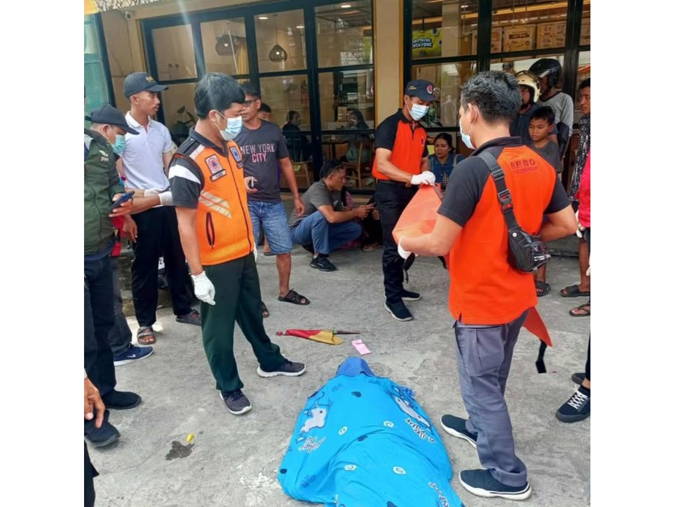 Jenazah Kadek Agus hendak dievakuasi petugas dari halaman toko roti ke RSUP Prof Dr IGNG Ngoerah Denpasar. (Bali Express/Istimewa)