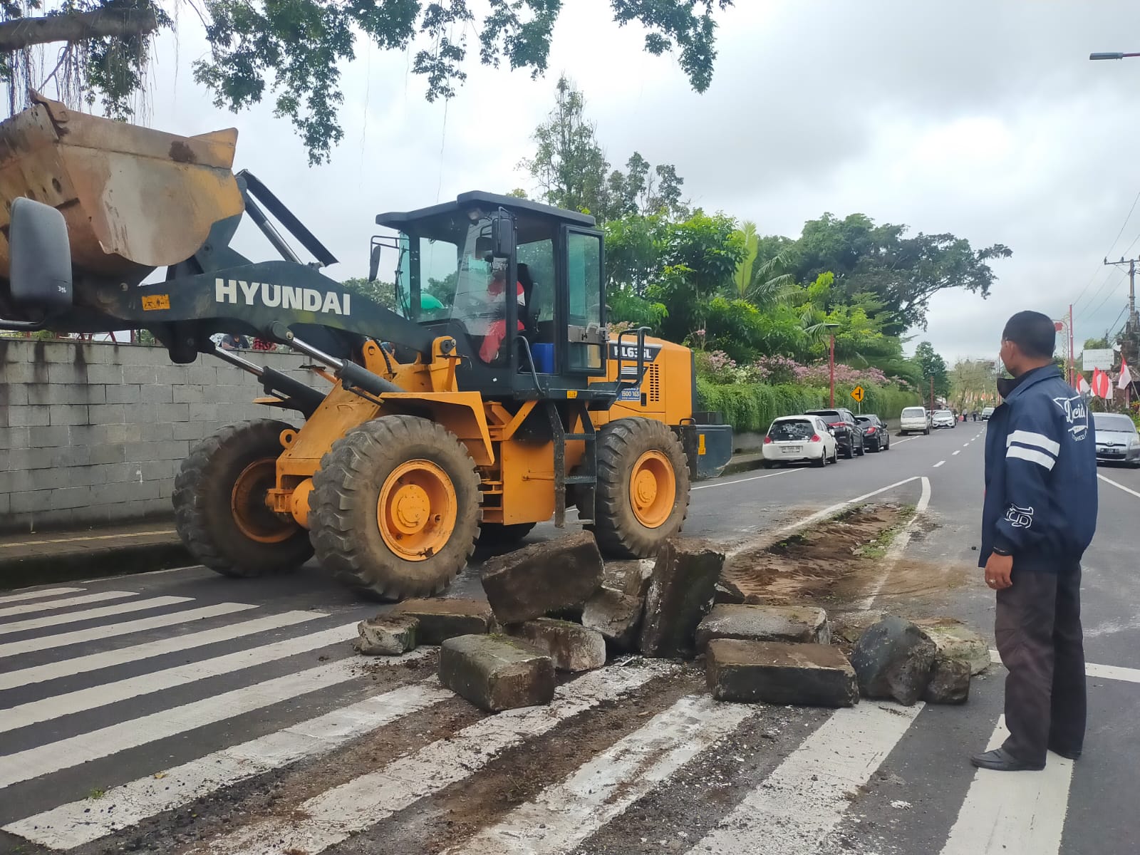 Loader dari Dinas Pekerjaan Umum Bangli membongkar median jalan di simpang tiga Jalan Brigjen Ngurah Rai-Jalan Lettu Lila, Rabu (16/7/2025).