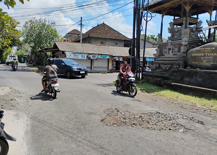 BAHAYA : Kondisi jalan yang rusak di barat Pasar Tusan, Desa Tusan, Kecamatan Banjarangkan, Klungkung.
