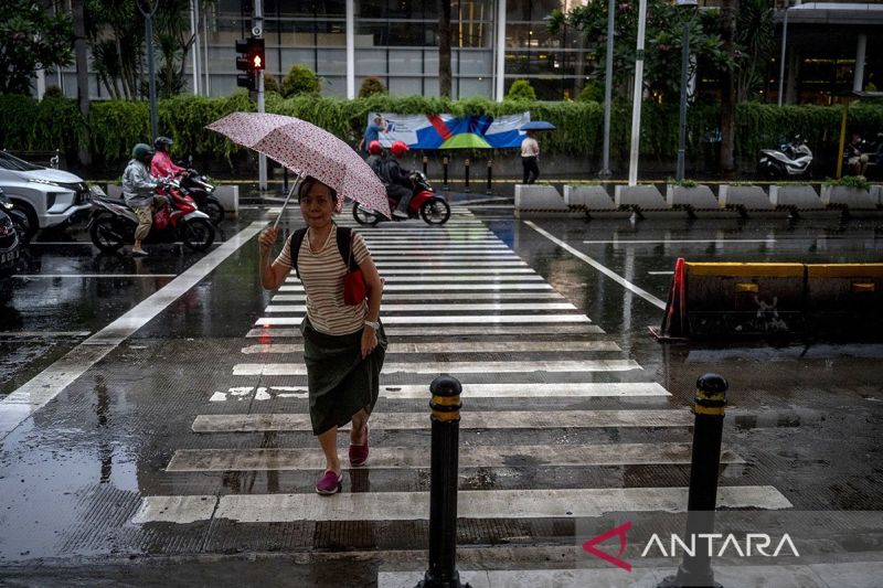 Seorang warga menggunakan payung saat turun hujan di kawasan Bundaran HI, Jakarta, Kamis (4/7/2024)
