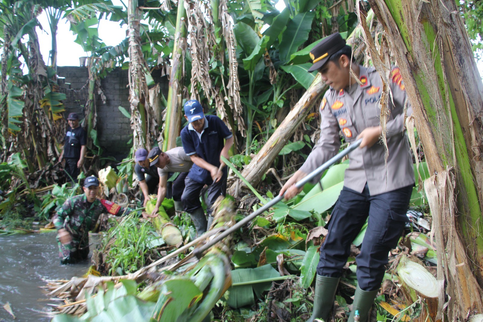 Kapolsek Kota Jembrana IPDA Ngr Agus Dwi Widiatmika Putra saat gotorng royong pasca banjir di Desa Budeng, Minggu (14/9).
