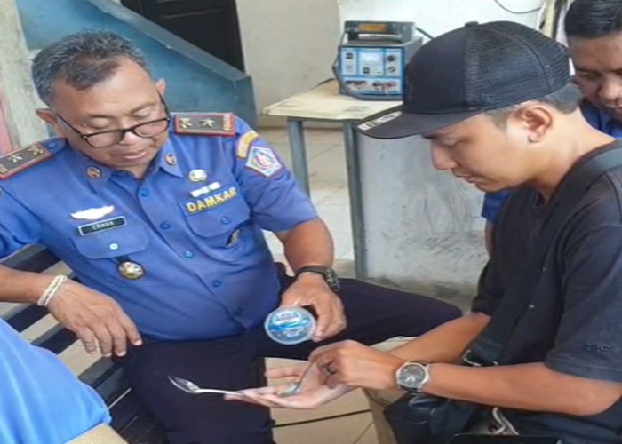 IPELEPASAN : Petugas membantu seorang warga bernama Riki, 31, asal Kampung Gelgel, yang mengalami kesulitan melepas cincin emas .