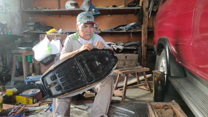 Nur Hamang sedang memperbaiki sadel pelanggannya di bengkel kecil miliknya.