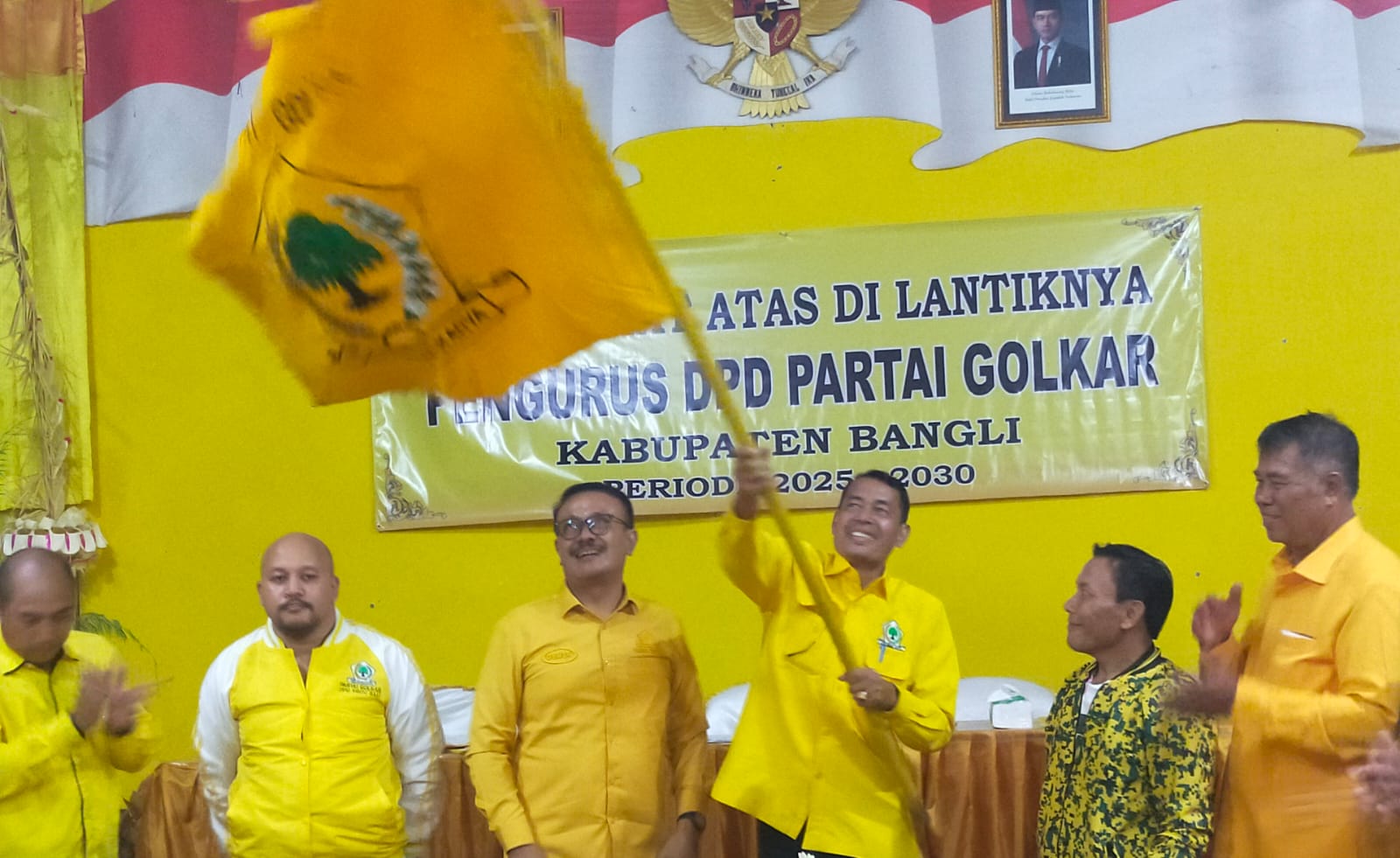 I Nyoman Budiada mengibarkan bendera Golkar usai terpilih menjadi ketua DPD II Golkar Bangli, Sabtu (11/10/2025).
