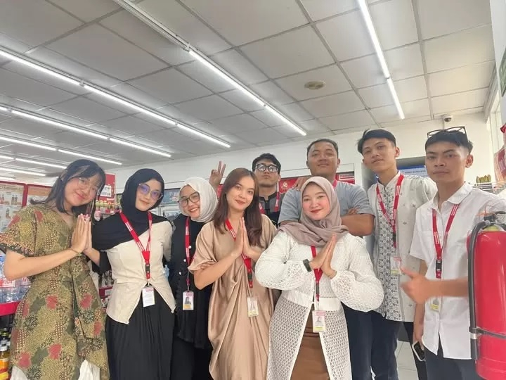 Pegawai Alfamart Dina Oktaviani (baju putih hijab krem) berdiri di depan pelaku Heryanto di foto bersama di Alfamart.