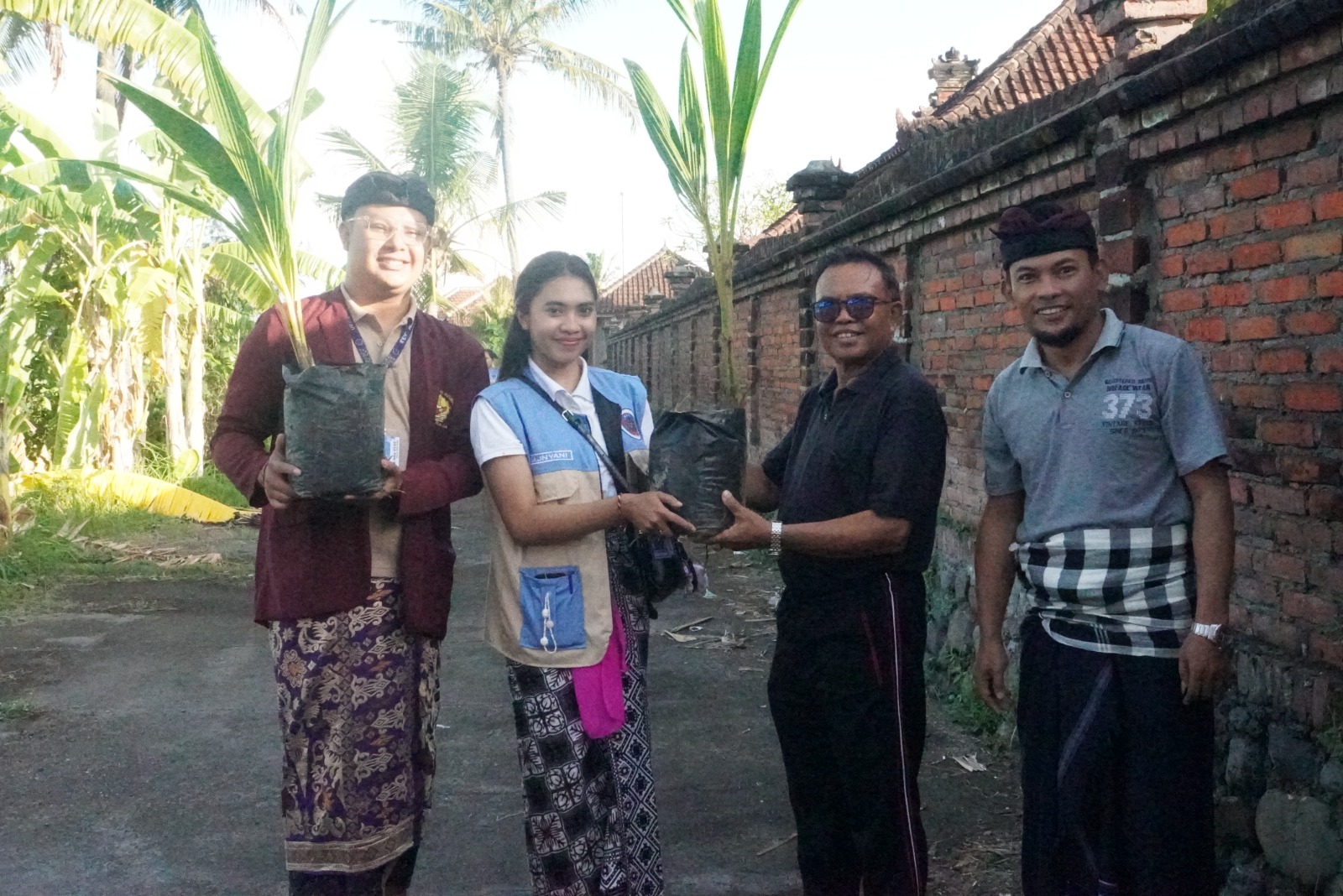 Mahasiswa KKN Institut Mpu Kuturan di Desa Poh Bergong saat membagikan puluhan pohon kelapa untuk ditanam