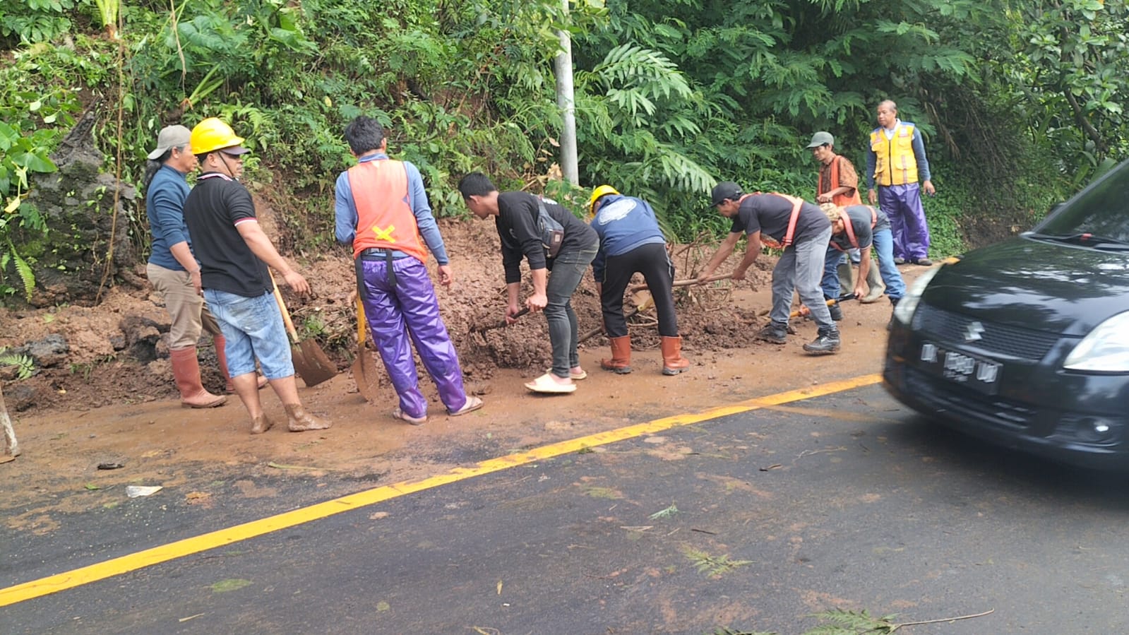 Pembersihan material longsor yang sempat menutup sebagian badan jalan di Desa Gitgit, Buleleng.