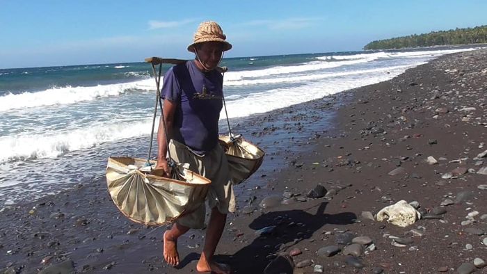 Pengambilan air laut untuk proses penggaraman menggunakan alat tradisional dari daun lontar di Desa Les.