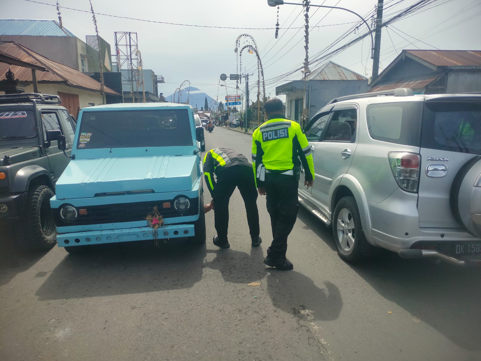Unit Lalu Lintas Polsek Kintamani menggembosi ban mobil yang parkir sembarangan di Jalan Raya Batur, Kamis (11/12/2025).