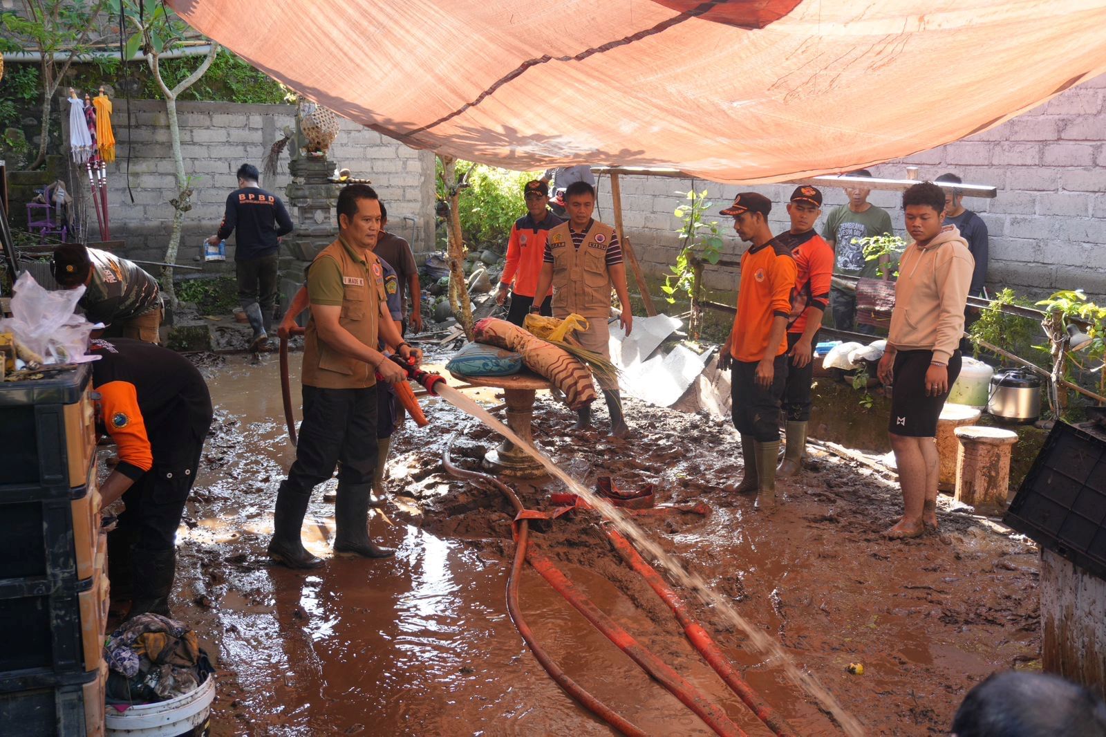 Bupati Jembrana I Made Kembang Hartawan menyerahkan bantuan kepada warga terdampak banjir bandang di Banjar Pasar, Desa Pekutatan, Kecamatan Pekutatan, Jumat (16/1/2026).