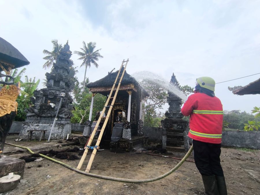 Petugas damkar saat melakukan pemadaman terhadap peristiwa kebakaran yang menghanguskan atap Gedong Pura Pungut Sari, Banjar Tengah, Desa Yehkuning, Kecamatan Jembrana, Minggu (8/2/2026).