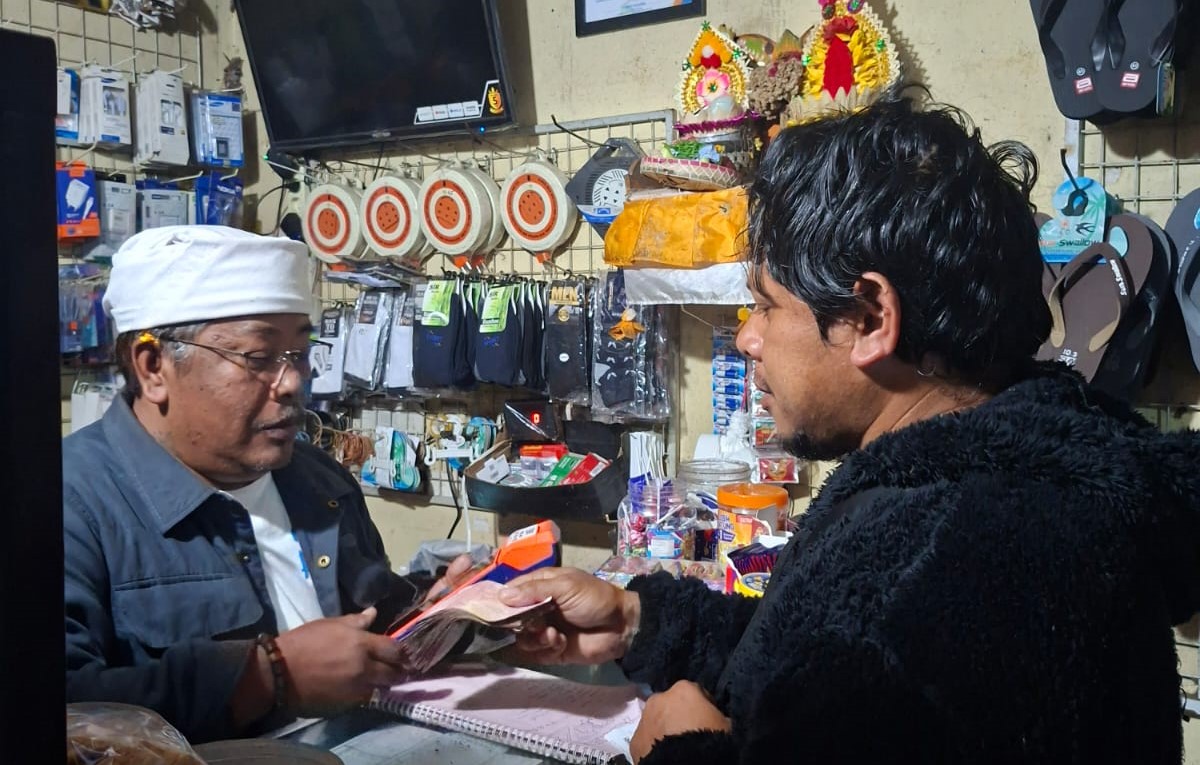 Jro Mangku Darsana (kiri) melayani transaksi di agen BRILink Omes Cell.