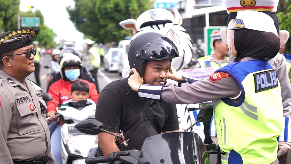 Anggota Polres Buleleng membagikan helm kepada pengguna jalan raya di Buleleng.