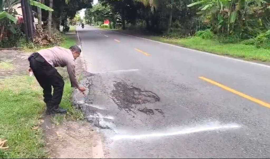 Bhabinkamtibmas memasang tanda bahaya untuk jalan berlubang di desa Musi, Gerokgak.