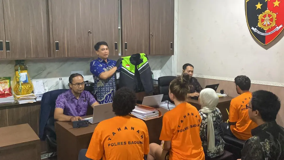 Petugas memeriksa tiga tersangka kasus video bermuatan s*ksual menggunakan atribut ojol. (Bali Express/Istimewa)