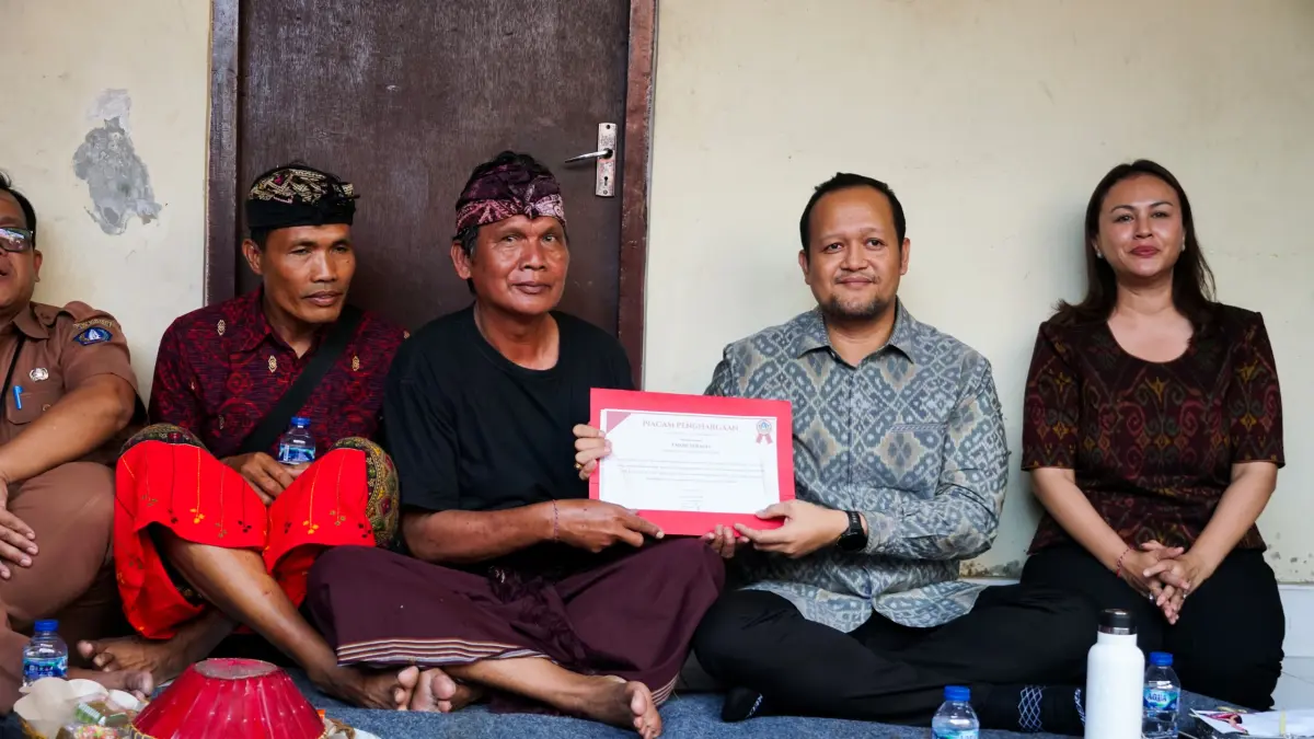 Wabup Bagus Alit Sucipta didampingi Ketua GOW Badung Nyonya Yunita Alit Sucipta menyerahkan Piagam Penghargaan Tertib Administrasi Pengurusan Akta Kematian dan Kartu Keluarga (KK) kepada ahli waris I Made Subagia di Banjar Belawan, Desa Dauh Yeh Cani, Abiansemal, Senin (27/7). (PROKOMPIM SETDA BADUNG)