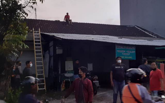 PROSES: Polisi dibantu warga dari atap mencoba meraih posisi P yang mengunci diri di warungnya. (istimewa)