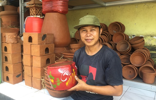 GERABAH: Komang Wira saat menunjukkan salah satu kerajinan gerabah di warung miliknya, Jumat (25/3). (PUTU RESA KERTAWEDANGGA/BALI EXPRESS)