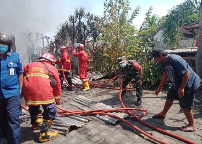 RESIKO : Petugas Damkar Klungkung berupaya memadamkan api di rumah warga di Desa Tangkas, Klungkung beberapa waktu lalu.
